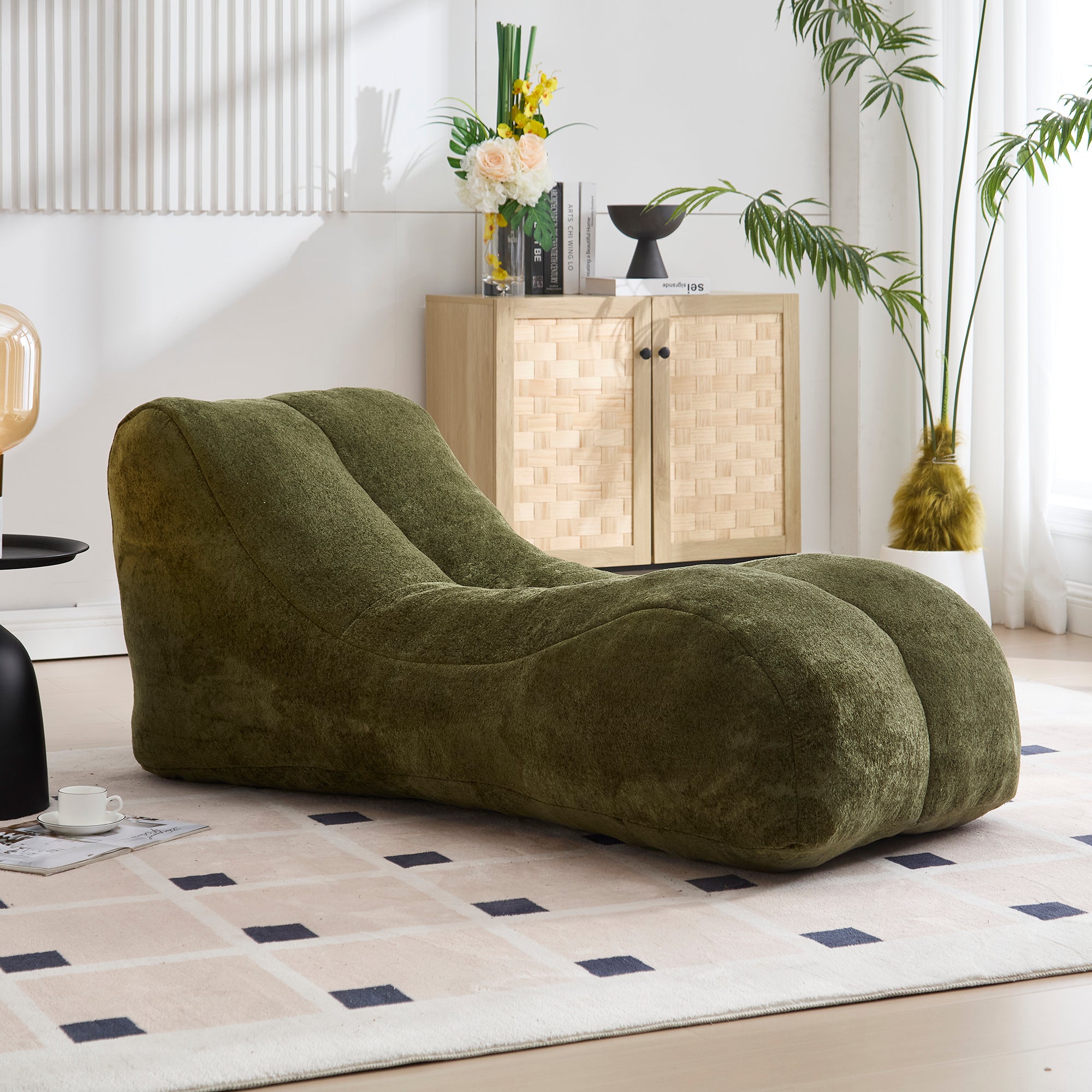 Green bean bag chair in a modern living room with a cabinet and plants.